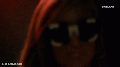 A Close Up Of A Woman Wearing Sunglasses And Hoop Earrings . GIF