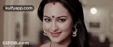 A Close Up Of A Woman With A Red Dot On Her Forehead Smiling . GIF