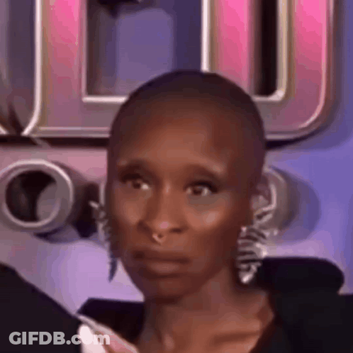 A Close Up Of A Woman With A Shaved Head And Earrings Making A Funny Face . GIF
