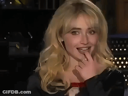 A Close Up Of A Woman With Blonde Hair Covering Her Mouth With Her Hand . GIF
