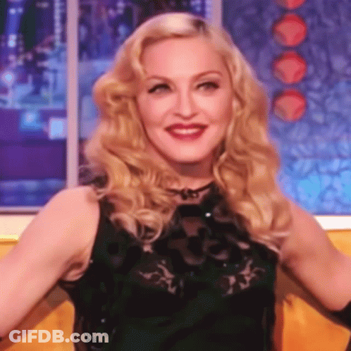 A Close Up Of A Woman With Blonde Hair Wearing A Black Dress GIF