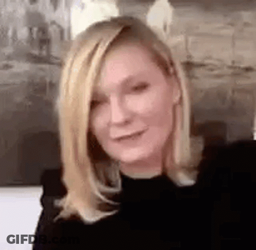 A Close Up Of A Woman With Blonde Hair Wearing A Black Shirt And Smiling . GIF