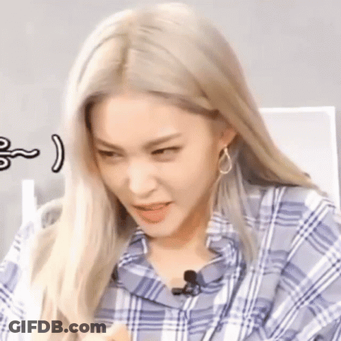 A Close Up Of A Woman With Blonde Hair Wearing A Plaid Shirt And Earrings Making A Funny Face . GIF