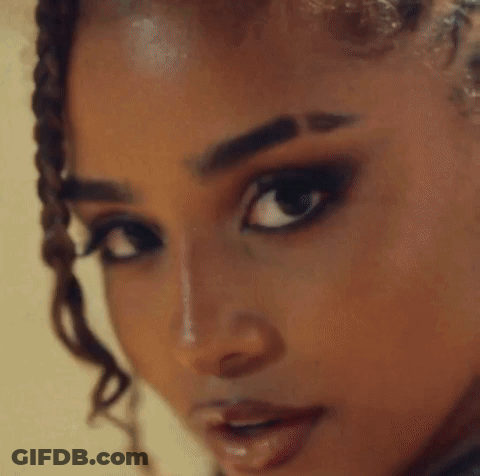 A Close Up Of A Woman With Braids And Hoop Earrings GIF