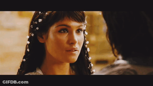 A Close Up Of A Woman With Pearls In Her Hair Looking At A Man GIF