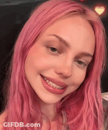 A Close Up Of A Woman With Pink Hair Smiling GIF
