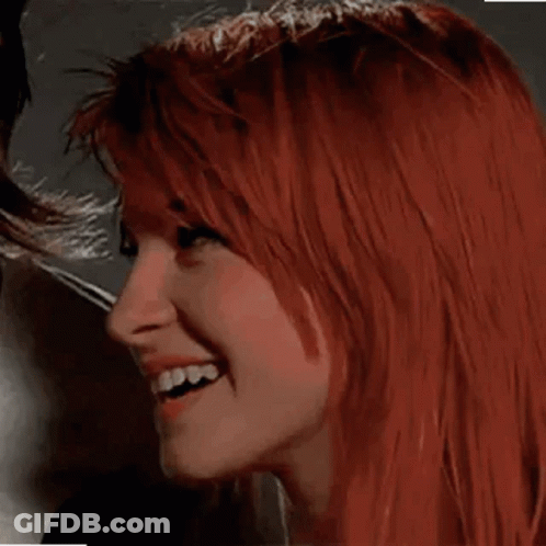 A Close Up Of A Woman With Red Hair Smiling And Looking At The Camera . GIF
