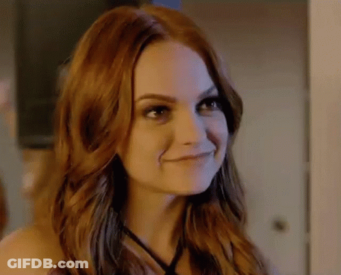 A Close Up Of A Woman With Red Hair Smiling In A Room . GIF