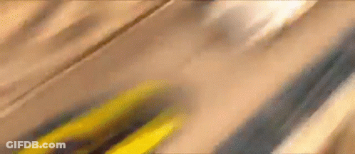 A Close Up Of A Yellow Car Driving Down A Wooden Road . GIF