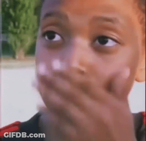 A Close Up Of A Young Boy Covering His Mouth With His Hand . GIF