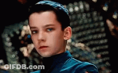A Close Up Of A Young Boy Wearing A Blue Jacket And Turtleneck . GIF