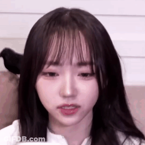 A Close Up Of A Young Girl With Long Hair And Bangs Looking At The Camera . GIF
