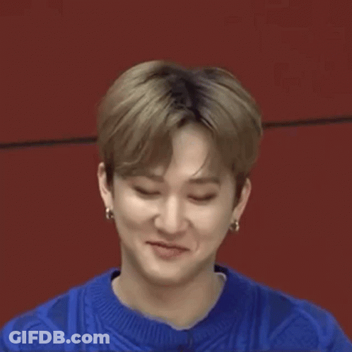 A Close Up Of A Young Man Making A Funny Face While Wearing A Blue Sweater And Earrings . GIF