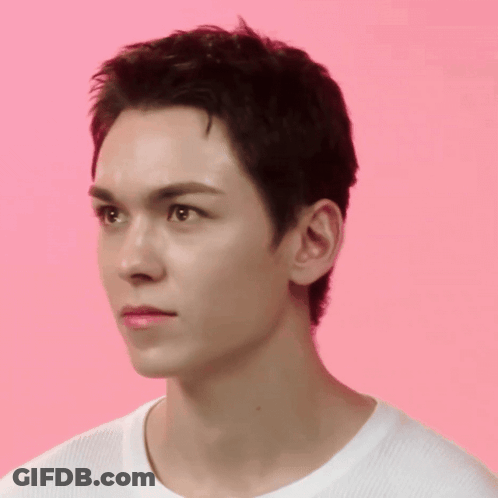 A Close Up Of A Young Man 'S Face Against A Pink Background GIF