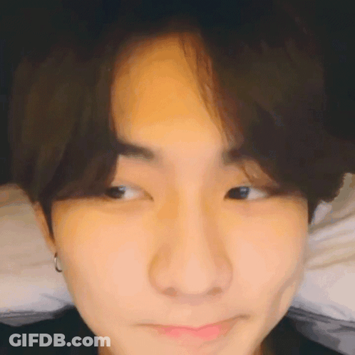 A Close Up Of A Young Man 'S Face Making A Funny Face While Laying On A Bed . GIF