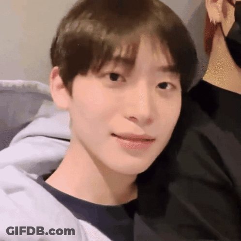 A Close Up Of A Young Man 'S Face Wearing A Black Shirt And A Gray Jacket . GIF