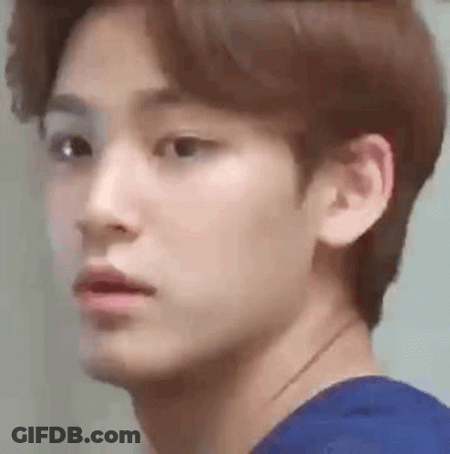 A Close Up Of A Young Man 'S Face Wearing A Blue Shirt And Looking At The Camera . GIF