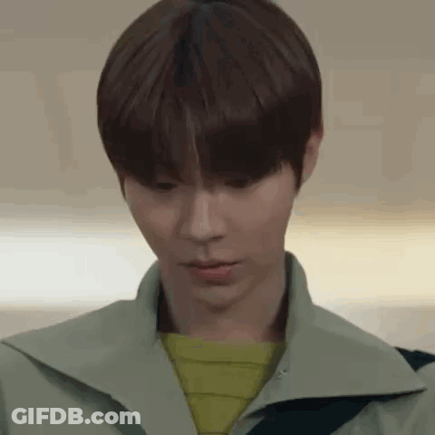 A Close Up Of A Young Man 'S Face Wearing A Green Jacket And A Yellow Sweater . GIF
