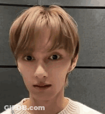 A Close Up Of A Young Man 'S Face Wearing A White Sweater And Making A Funny Face . GIF