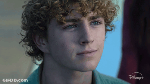 A Close Up Of A Young Man 'S Face With A Disney Logo In The Background GIF