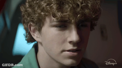 A Close Up Of A Young Man 'S Face With A Disney + Logo In The Background GIF
