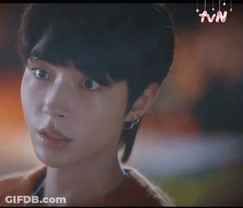 A Close Up Of A Young Man 'S Face With A Mullet Hairstyle And Earrings . GIF