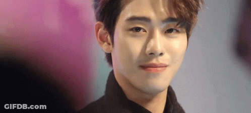 A Close Up Of A Young Man 'S Face With A Pink Background Looking At The Camera . GIF