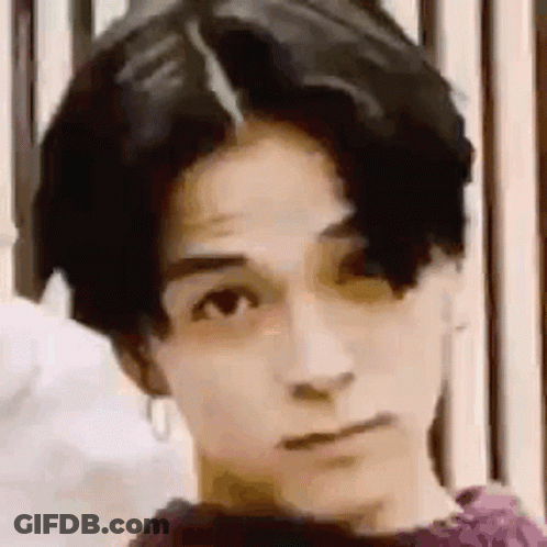 A Close Up Of A Young Man 'S Face With A Purple Shirt On . GIF