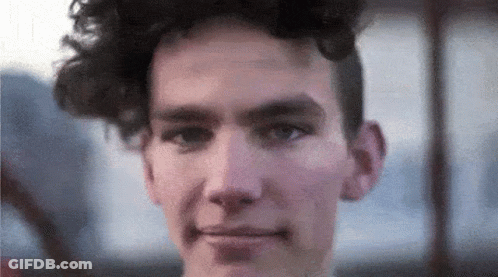 A Close Up Of A Young Man 'S Face With Curly Hair GIF