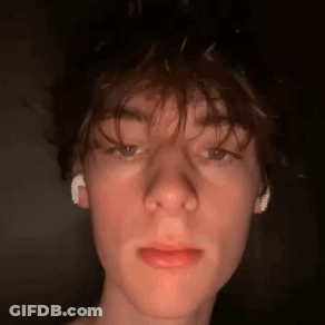 A Close Up Of A Young Man 'S Face With Ear Buds In His Ears . GIF