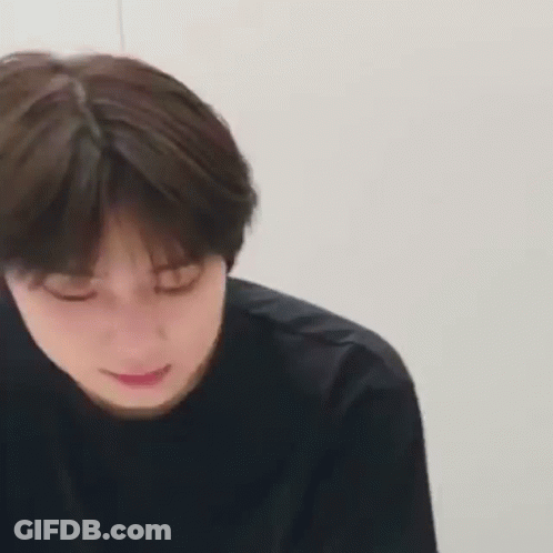 A Close Up Of A Young Man 'S Face With His Eyes Closed And A Black Shirt On . GIF