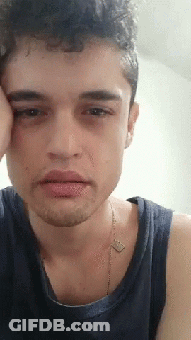 A Close Up Of A Young Man 'S Face With His Hand On His Face . GIF