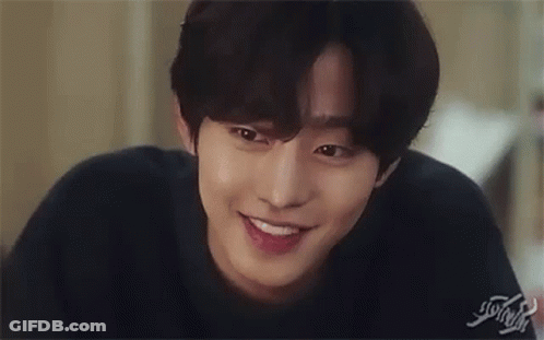 A Close Up Of A Young Man Smiling And Touching His Face . GIF