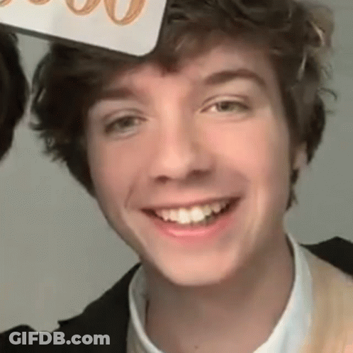 A Close Up Of A Young Man Smiling While Wearing A Hat On His Head . GIF