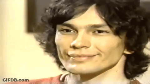 A Close Up Of A Young Man With Curly Hair Smiling . GIF
