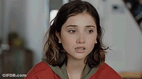 A Close Up Of A Young Woman Wearing A Red Sweater And Earrings . GIF