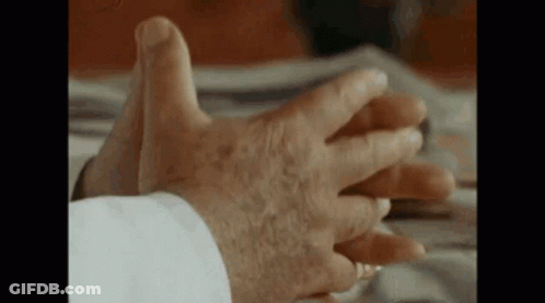A Close Up Of An Elderly Man 'S Hands On A Bed . GIF