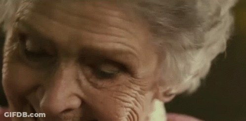A Close Up Of An Elderly Woman 'S Face With Wrinkles And A Pink Shirt . GIF