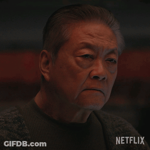 A Close Up Of An Older Man 'S Face With A Netflix Logo Behind Him GIF