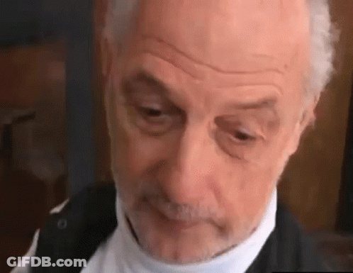 A Close Up Of An Older Man With A Beard Wearing A Black Jacket And A White Shirt . GIF