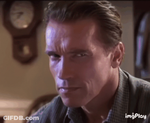 A Close Up Of Arnold Schwarzenegger 'S Face With A Clock In The Background . GIF