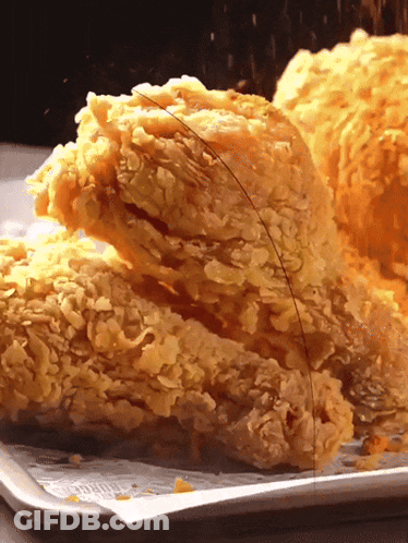 A Close Up Of Fried Chicken On A Tray With A Piece Missing GIF