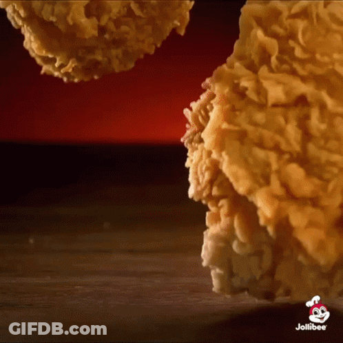 A Close Up Of Fried Chicken On A Wooden Table With A Jollibee Logo In The Corner . GIF