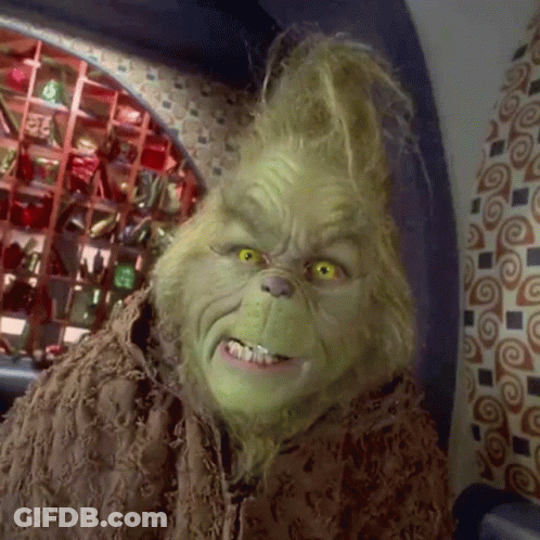 A Close Up Of Grinch 'S Face In A Room With A Patterned Wall GIF