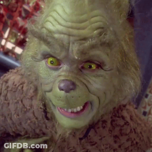 A Close Up Of Grinch 'S Face With Yellow Eyes And A Pink Teeth GIF