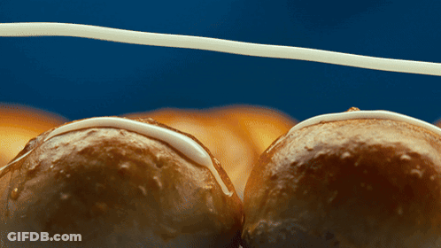 A Close Up Of Two Glazed Doughnuts On A Blue Surface GIF