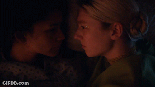 A Close Up Of Two Women Looking At Each Other In A Dark Room GIF