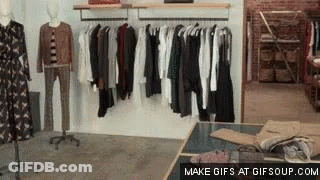 A Clothing Store With Clothes Hanging On Racks And A Table GIF