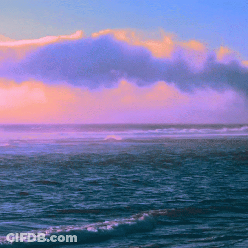 A Cloudy Sky Over The Ocean With Waves Crashing On The Shore GIF