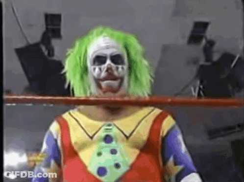 A Clown In A Wrestling Ring With Green Hair And A Tie GIF